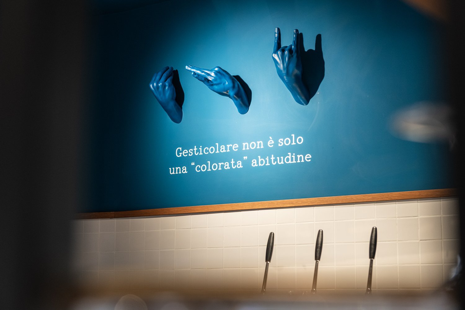 Le mani in ceramica blu e la frase «Gesticolare non è solo una colorata abitudine»